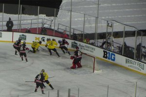 Ohio State player with puck as two Michigan players converge