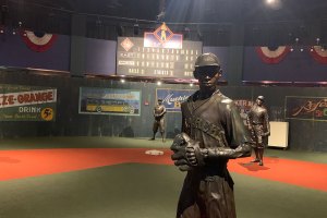 Three statues with scoreboard beyond